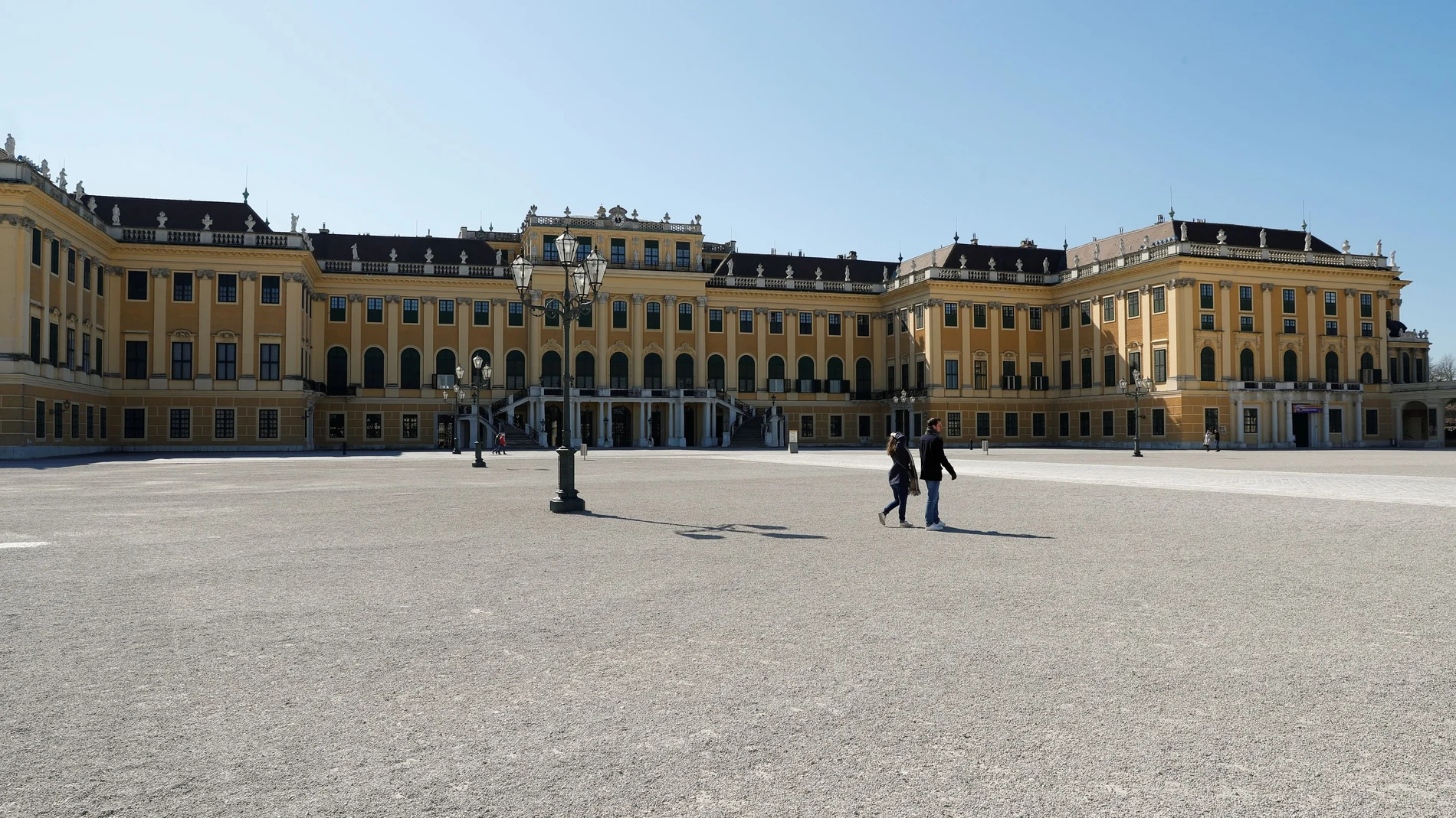 A couple walks past imperial Schoenbrunn palace in Vienna