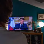 Un hombre ve el mensaje televisado del presidente francés Emmanuel Macron hoy lunes.