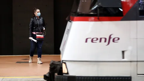 Una mujer, protegida con mascarilla, observa la llegada de su tren en la estación de Cercanías de Atocha, este lunes, en Madrid.