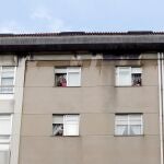 Miembros de una familia saludan desde las ventanas de su piso en Ferrol.