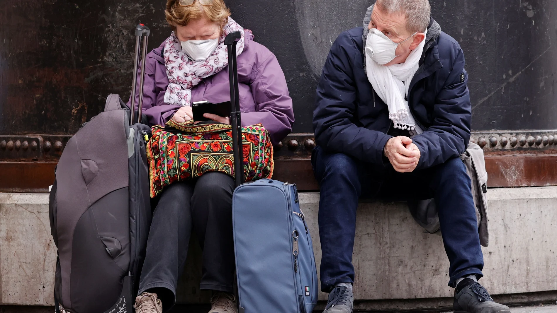 People wearing protective face masks wait in front of Gare du Nord railway station in Paris
