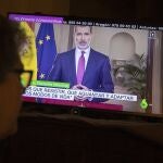 A woman watches Spanish King Felipe VI speak in a televised address to the nation in Madrid, Spain, Wednesday, March 18, 2020. Spain will mobilize 200 billion euros or the equivalent to one fifth of the country's annual output in loans, credit guarantees and subsidies for workers and vulnerable citizens, Prime Minister Pedro Sanchez announced Tuesday. For most people, the new COVID-19 coronavirus causes only mild or moderate symptoms. For some it can cause more severe illness. (AP Photo/Paul White)