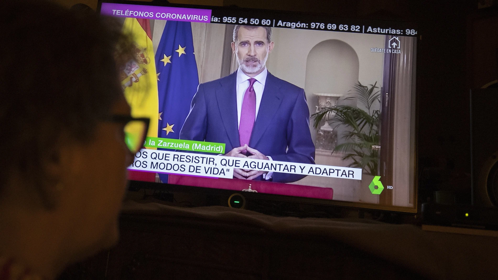 A woman watches Spanish King Felipe VI speak in a televised address to the nation in Madrid, Spain, Wednesday, March 18, 2020. Spain will mobilize 200 billion euros or the equivalent to one fifth of the country's annual output in loans, credit guarantees and subsidies for workers and vulnerable citizens, Prime Minister Pedro Sanchez announced Tuesday. For most people, the new COVID-19 coronavirus causes only mild or moderate symptoms. For some it can cause more severe illness. (AP Photo/Paul White)