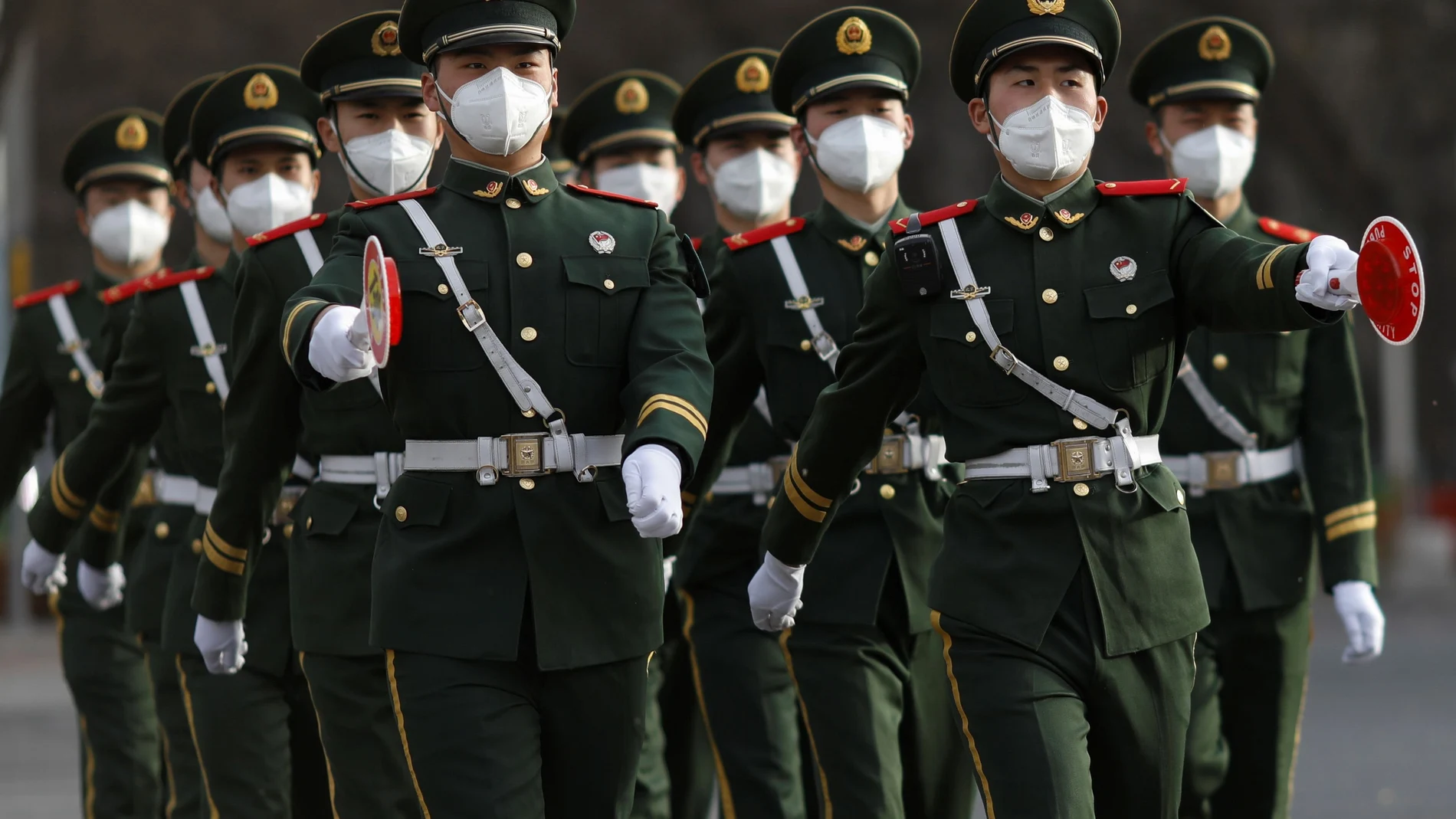 Paramilitary officers wearing face masks to contain the spread of coronavirus disease (COVID-19) walk along a street in Beijing