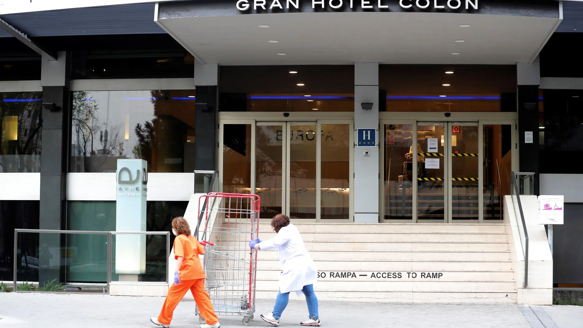 Dos empleadas con máscaras sanitarias pasan frente al hotel Gran Hotel Colon de la cadena Ayre, perteneciente a la empresa ibicenca Palladium Hotel Group, que acoge a partir de este jueves a pacientes de la Comunidad de Madrid con motivo de la crisis de la pandemia de coronavirus. EFE/Juanjo Martín