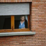 Una persona mayor mira por la ventana el cuarto día de confinamiento
