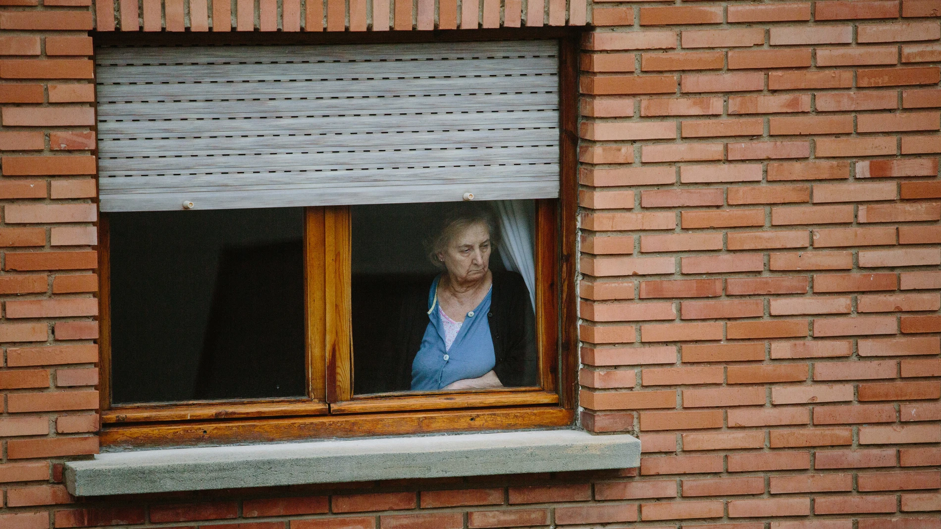 Una persona mayor mira por la ventana el cuarto día de confinamiento