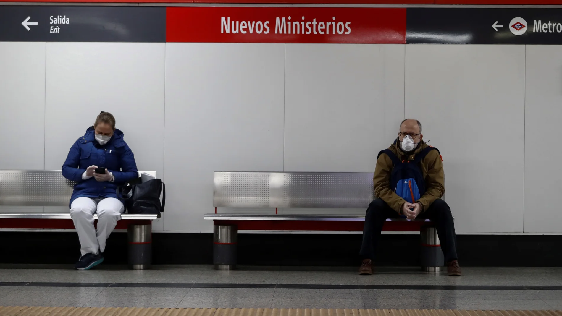 Dos usuarios protegidos con marcarillas respetan la distancia de seguridad mientras esperan la llegada del tren en la estación de Cercanías de Nuevos Ministerios de Madrid