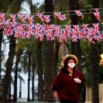 Una turista con máscara pasa por debajo de banderas británicas colgadas en una de las calles de la zona inglesa de Benidorm