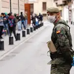 Un militar del Ejército de Tierra mantiene orden ante un comedor social de la capital durante el estado de alarma