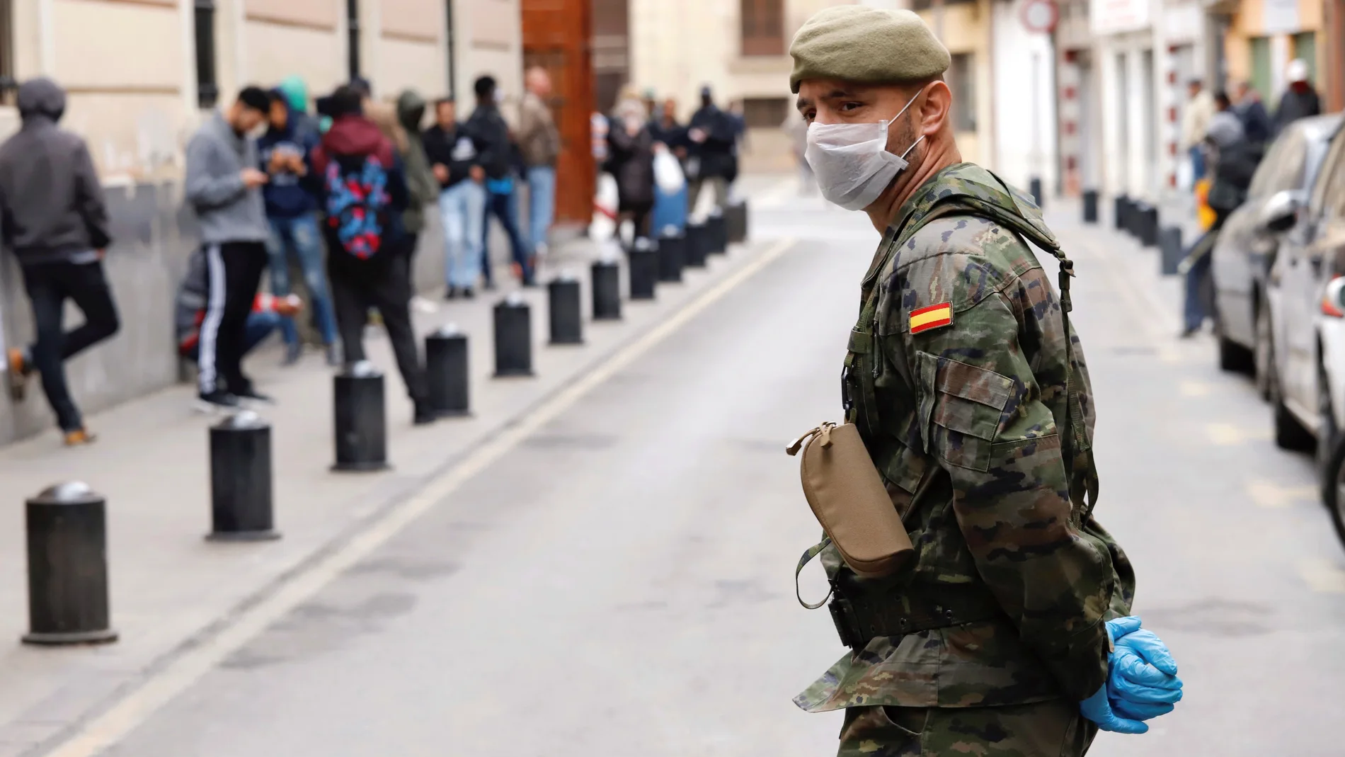 Un militar del Ejército de Tierra mantiene orden ante un comedor social de la capital durante el estado de alarma