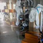 Varios ataúdes y varios trajes de protección en un pasillo del Tanatorio Crematorio Mémora Coslada