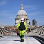 Un trabajador de la construcción cruza el puente del Milenio, frente a la catedral de San Pablo, en Londres/EFE