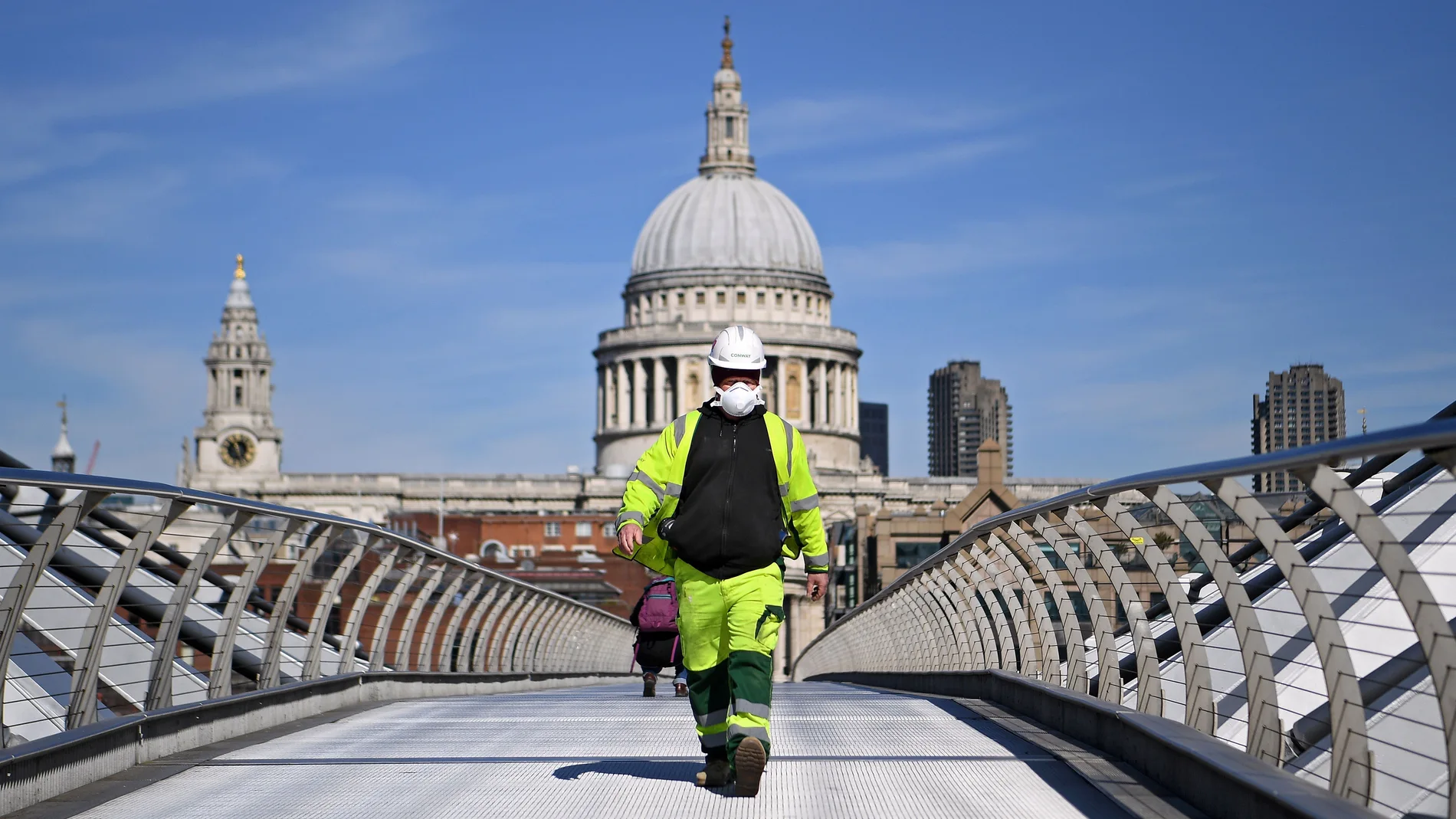 Un trabajador de la construcción cruza el puente del Milenio, frente a la catedral de San Pablo, en Londres/EFE
