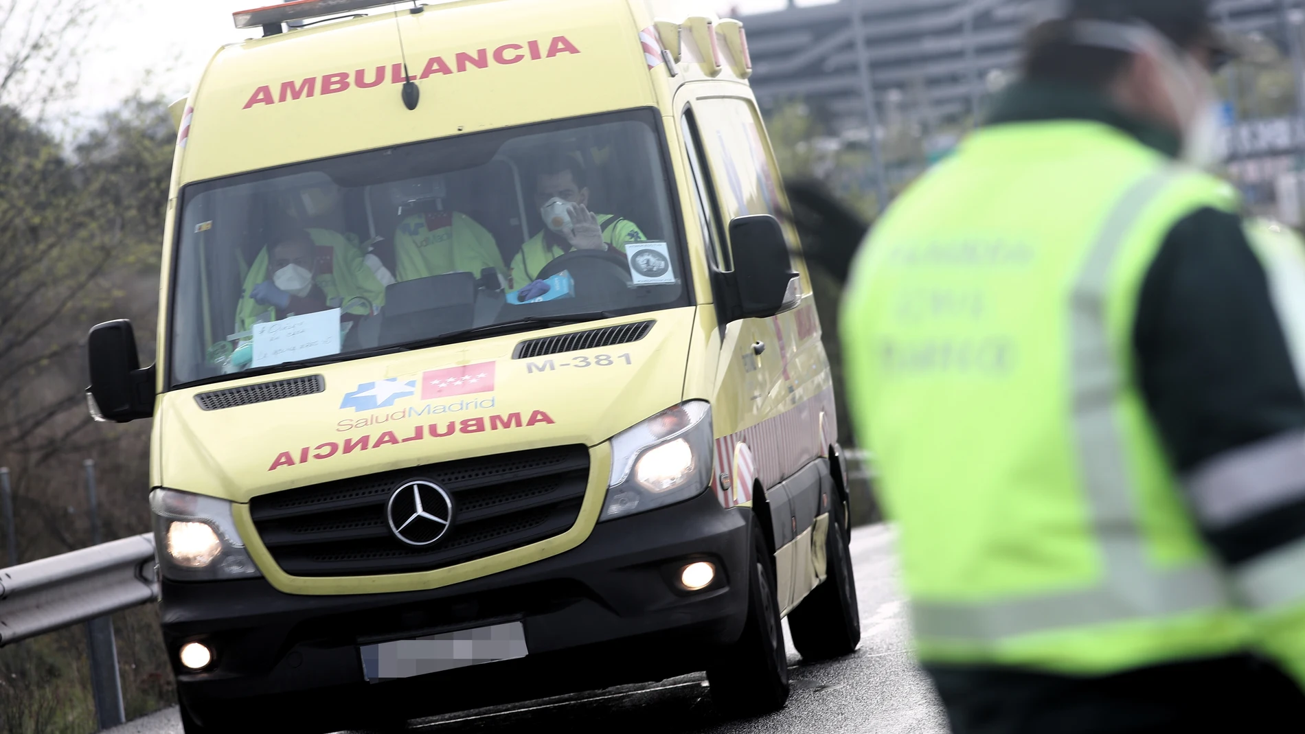 Sanitarios del SAMUR 112 de la Comunidad de Madrid totalmente protegidos conducen una ambulancia que se dirige a la entrada del recinto de Ifema