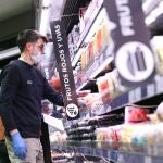 arias personas hacen la compra con mascarilla y guantes en un supermercado en Madrid