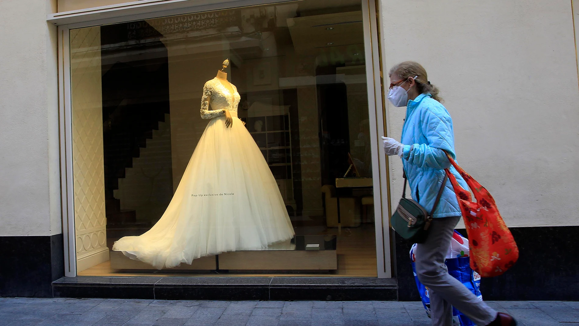 Una transeúnte pasa ante una tienda de trajes de novias en Sevilla 