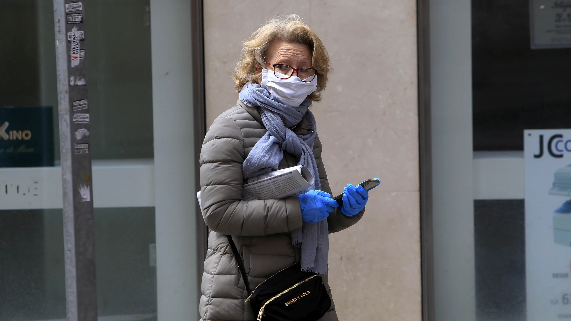 Una mujer se protege con guantes y mascarilla para salir a la calle en Sevilla