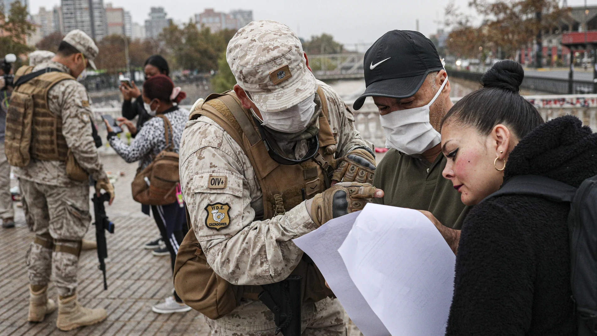 Un soldado revisa el salvoconducto de una mujer para acceder a una zona sometida a curantena en Santiago de Chile/AP