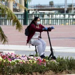 Una trabajadora de desplaza en un patinete protegida con una mascarilla por una calle de Málaga. EFE/Daniel Pérez