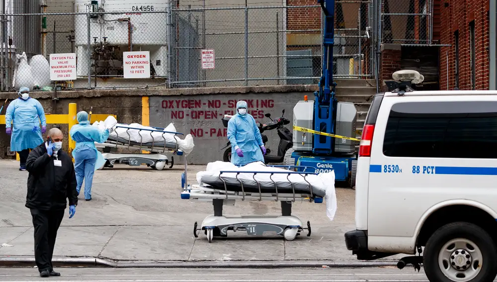 Un grupo de trabajadores trasladan cadáveres en las inmediaciones del Hospital Central de Brooklyn, en Nueva York