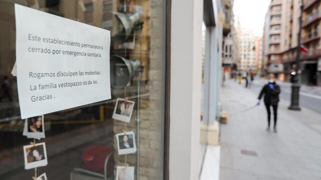 Cartel en la ventana de un establecimiento cerrado en una calle prácticamente vacía