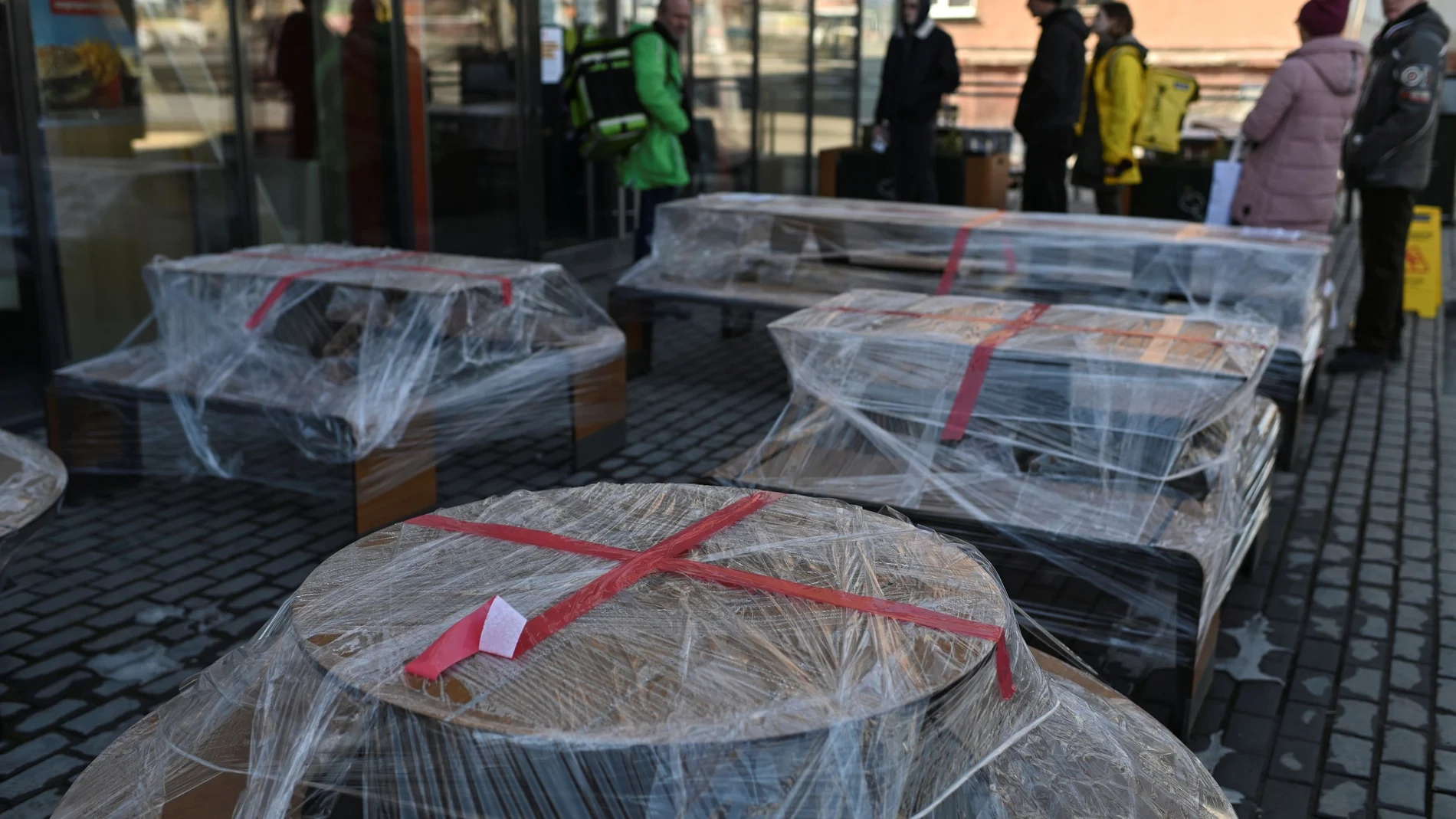 People gather near polythene-wrapped tables outside a McDonald's restaurant in Omsk
