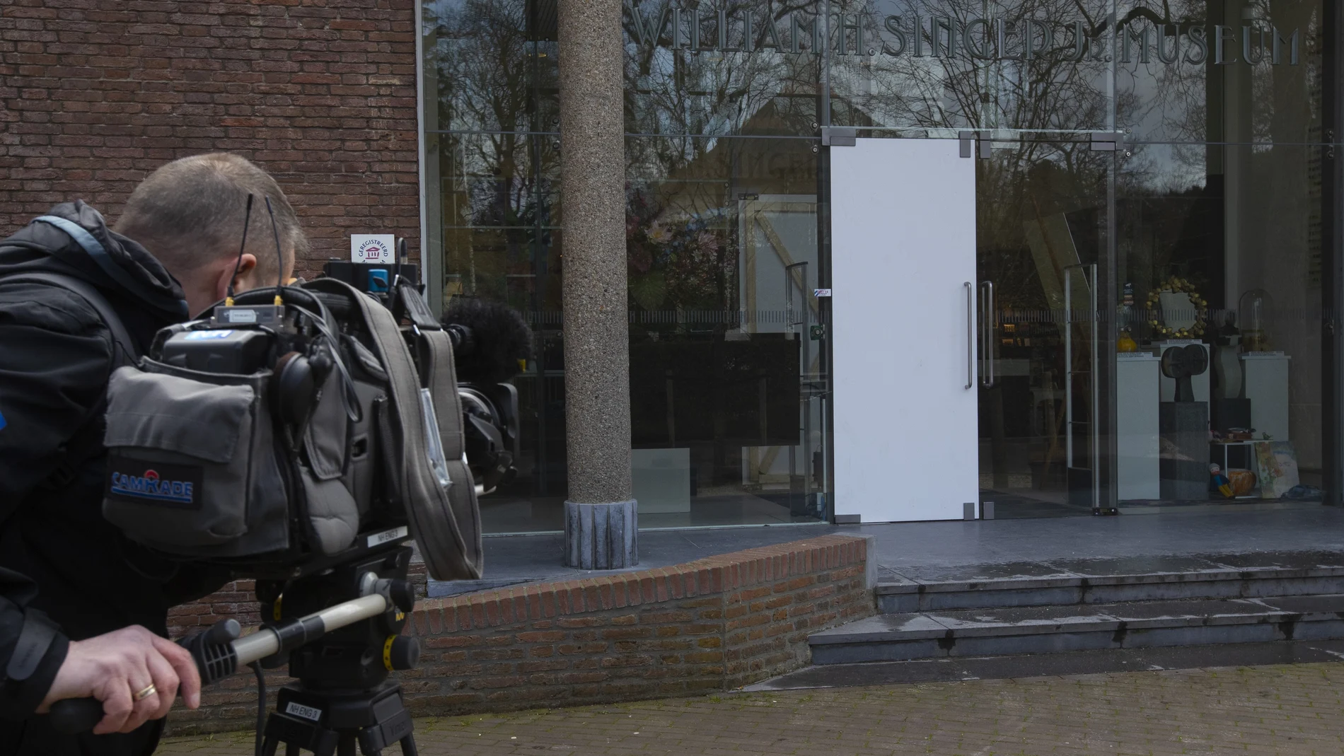 A cameraman films the glass door which was smashed during a break-in at the Singer Museum in Laren, Netherlands, Monday March 30, 2020. Police are investigating a break-in at a Dutch art museum that is currently closed because of restrictions aimed at slowing the spread of the coronavirus, the museum and police said Monday. (AP Photo/Peter Dejong)