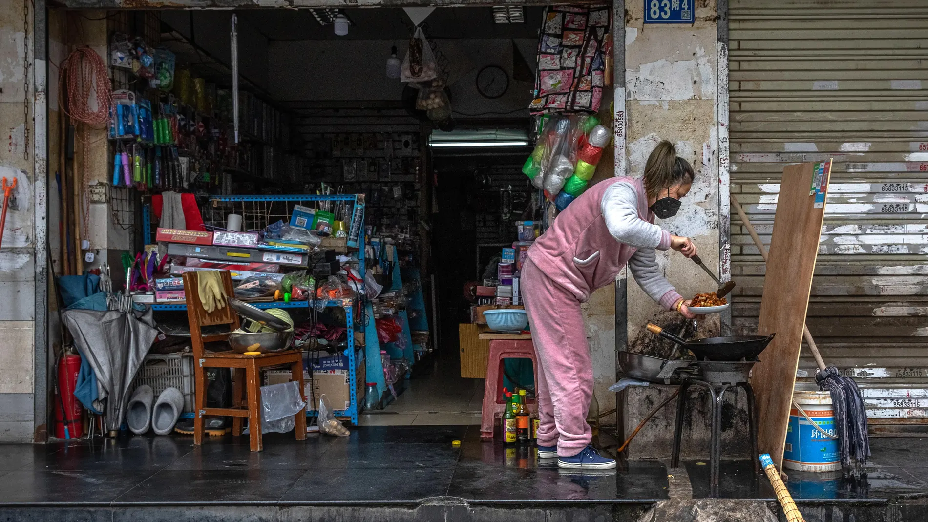 Una mujer en cocina cerca de una tienda en una calle de Wuhan