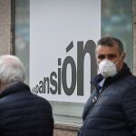 Un hombre con una mascarilla junto a una sucursal bancaria en Alcalá de Henares el pasado miércoles