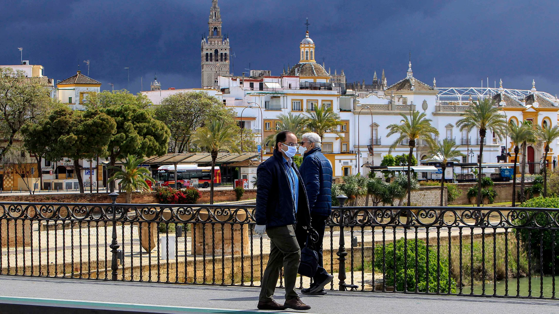 Dos hombres con mascarillas cruzando el puente de Triana, en Sevilla