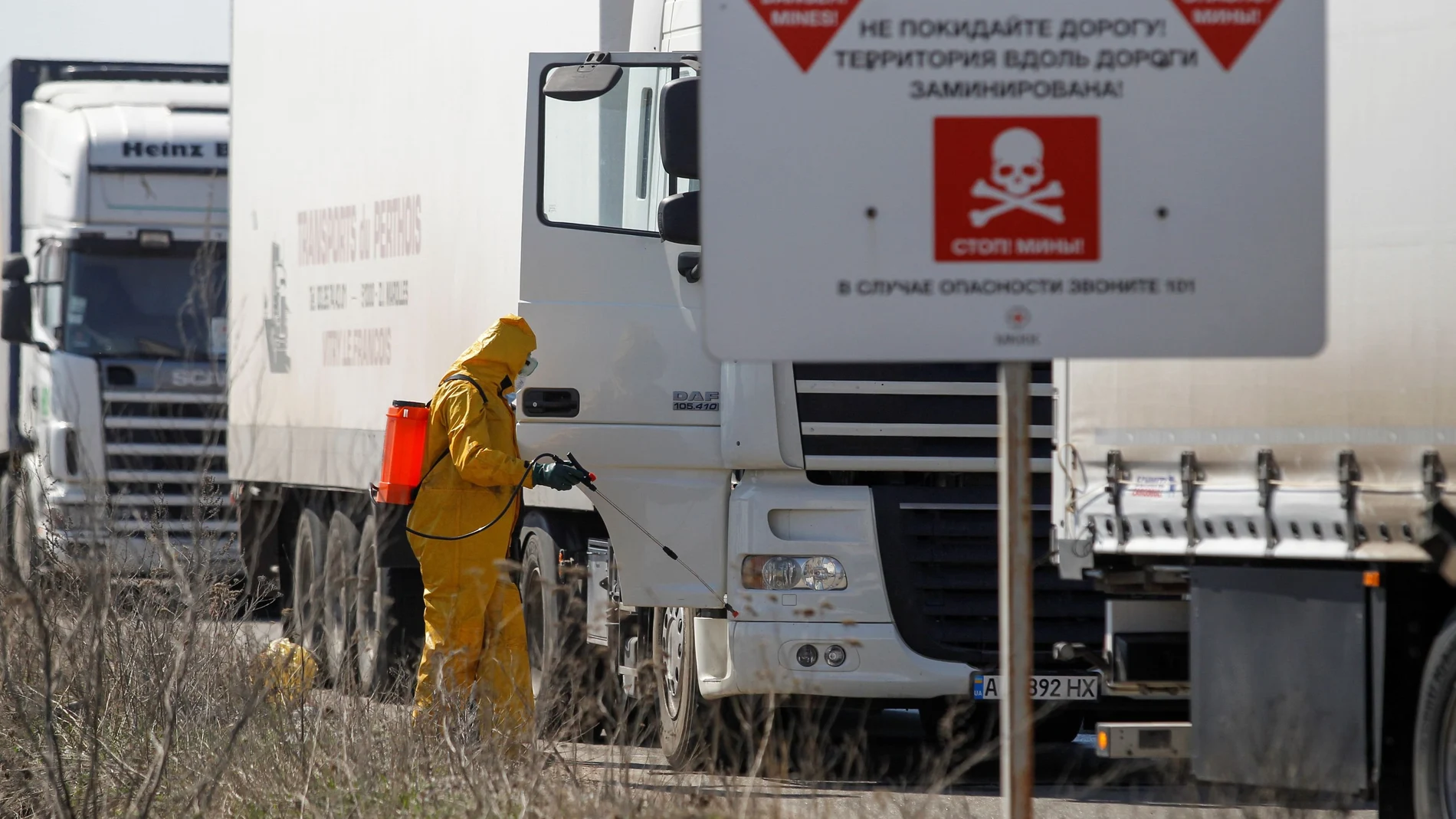 Specialists sanitize a truck convoy of the International Committee of the Red Cross at a check point in Donetsk region