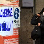 Una mujer pasea por Milán ante una obra con el cartel "Máscaras disponibles"/EFE