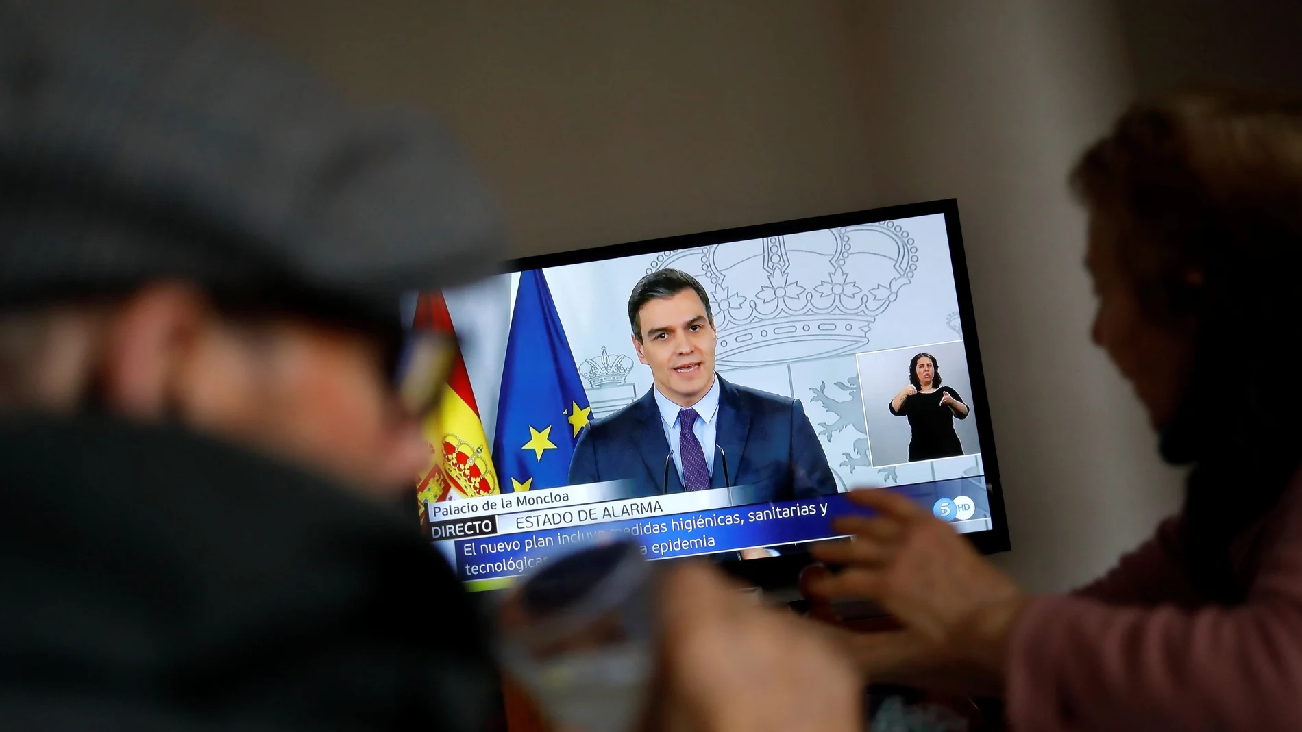 An elderly couple eats lunch at their home as they watch Spanish Prime Minister Pedro Sanchez on a television screen during a live news conference, due to the coronavirus disease (COVID-19) outbreak, in Ronda, southern Spain April 4, 2020. REUTERS/Jon Nazca