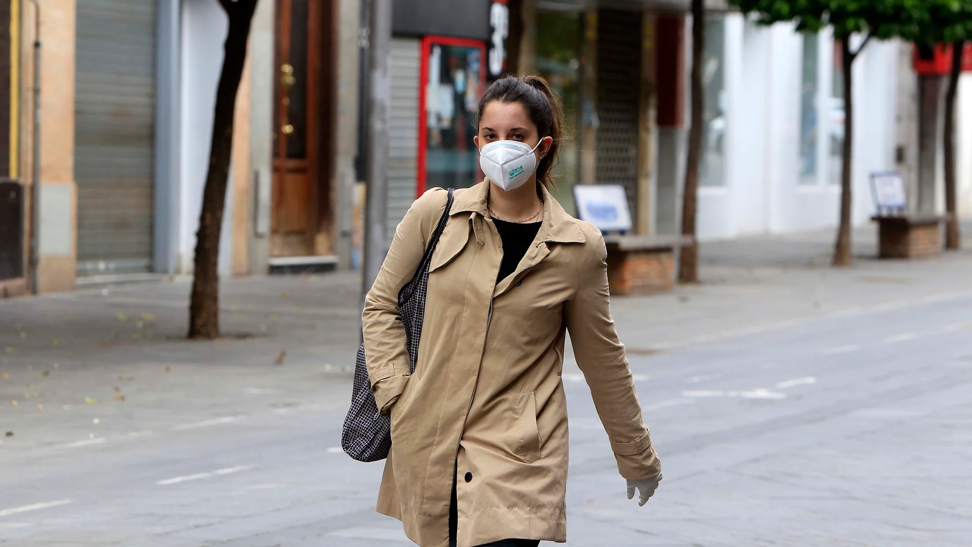 Una joven pasea por el centro de Sevilla protegida con una mascarilla