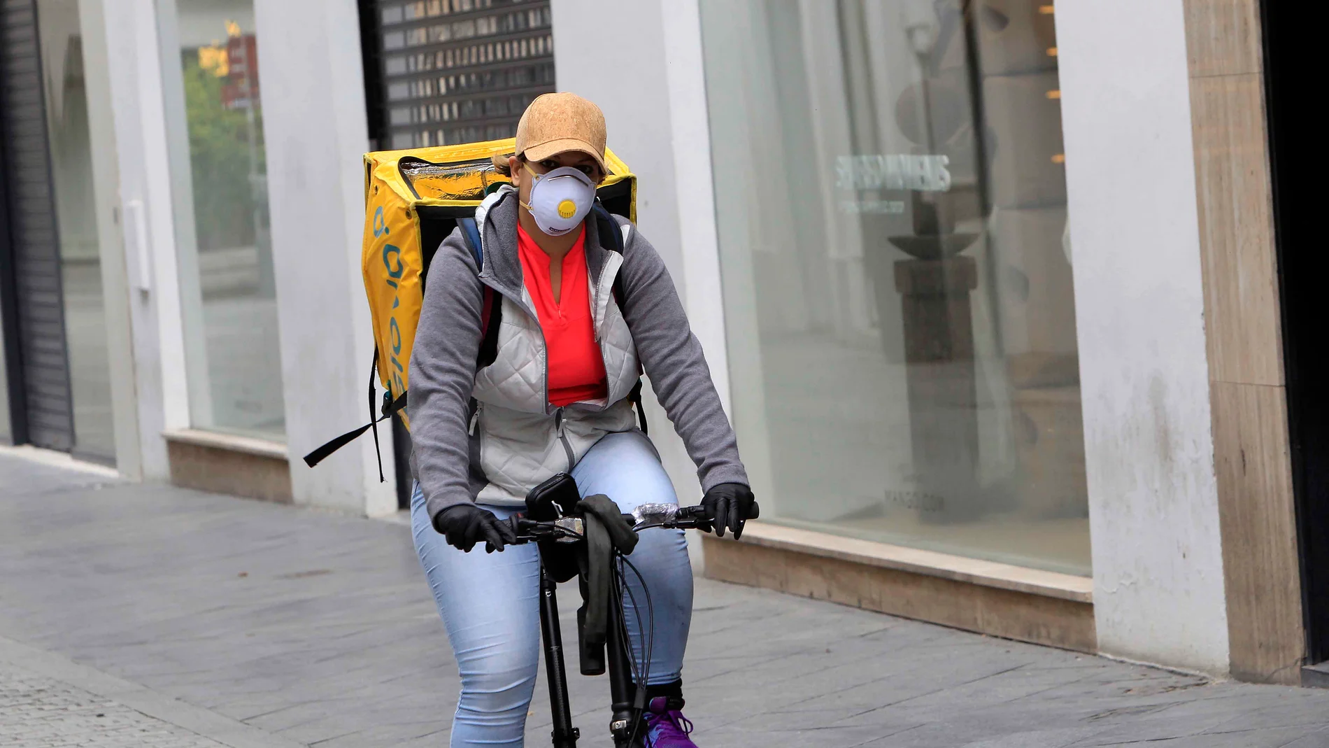 Una repartidora se protege con una mascarilla en el centro de la capital andaluza