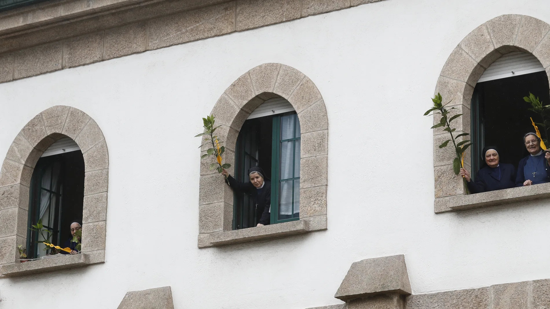 Religiosas salen al balcón con ramos y palmas en domingo de Ramos, en confinamiento.