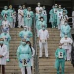 Sanitarios protegidos con mascarillas sujetan crespones negros durante el minuto de silencio en la entrada del Hospital Doctor Peset por la técnica de enfermería fallecida por coronavirus