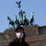 Un hombre con máscara frente a la Puerta de Brandenburgo, en Berlín