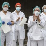 Sanitarios protegidos con mascarillas aplauden conmocionados tras el minuto de silencio en la entrada del Hospital Doctor Peset por la técnica de enfermería fallecida por coronavirus, en Valencia