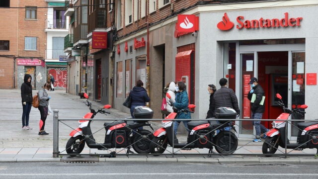 Varias personas esperan para entrar a una oficina del Banco Santander