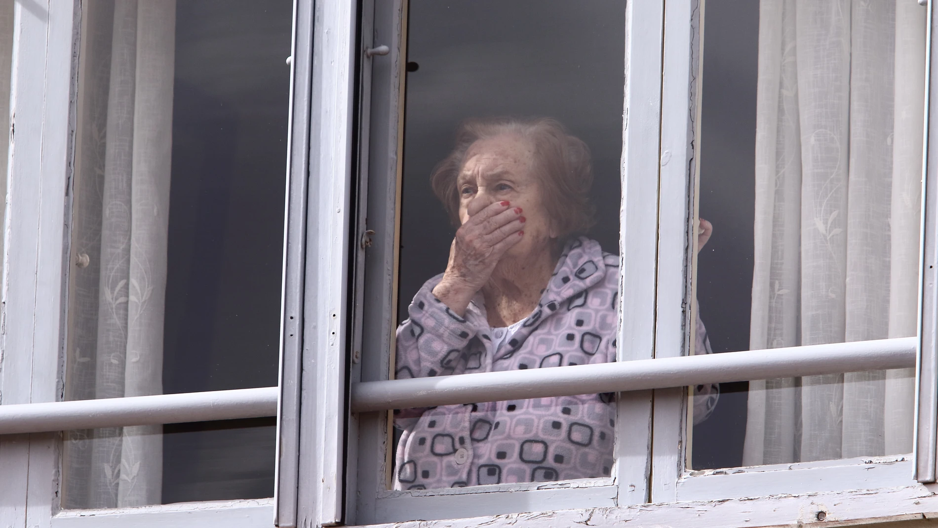 Una mujer mira preocupada desde su casa durante el Estado de Alarma en Ponferrada