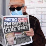 Un londinense con máscara lee el periódico con la portada dedicada a Boris Johnson