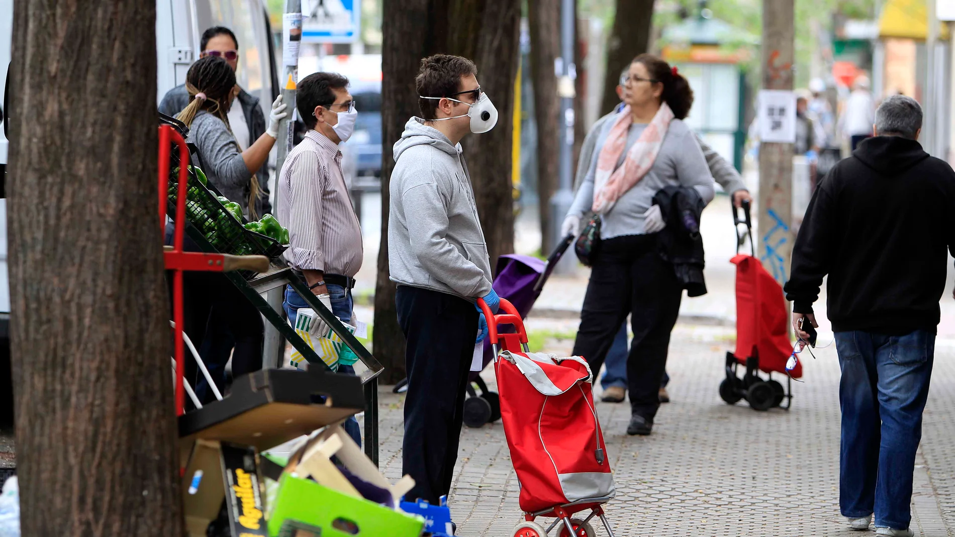 Un grupo de personas guarda la distancia de seguridad a las puertas de un supermercado de Sevilla