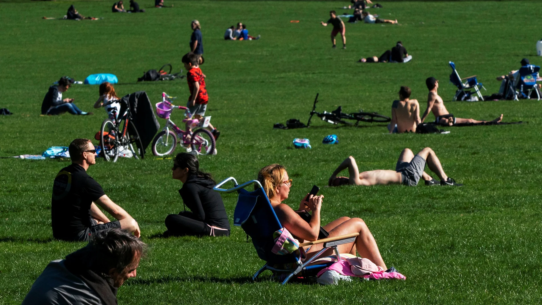 Decenas de personas aprovechan el día soleado en Central Park, en el centro de Nueva York, tratando de mantener la distancia social entre ellos