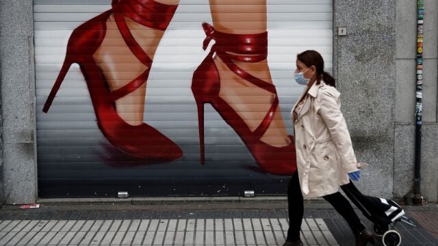 Una mujer que va a hacer la compra pasa ante un negocio cerrado