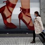 Una mujer que va a hacer la compra pasa ante un negocio cerrado