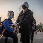 Pasajeros con equipo de protección en la estación de tren de Wuhan,China .