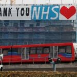 Un tren pasa junto a un cartel que da las gracias al Sistema Nacional de Salud (NHS) de Reino Unido/REUTERS