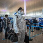 Un hombre ataviado con mono blanco para tomar un avión hoy en el aeropuerto de Wuhan